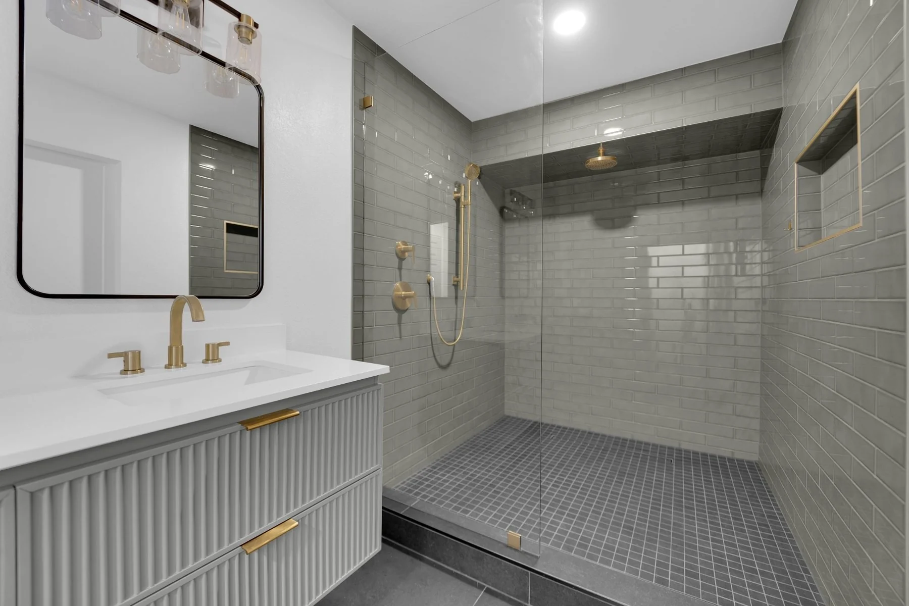 Green tile shower with rain head, handheld shower, recessed niche, mosaic floor, and frameless glass panel