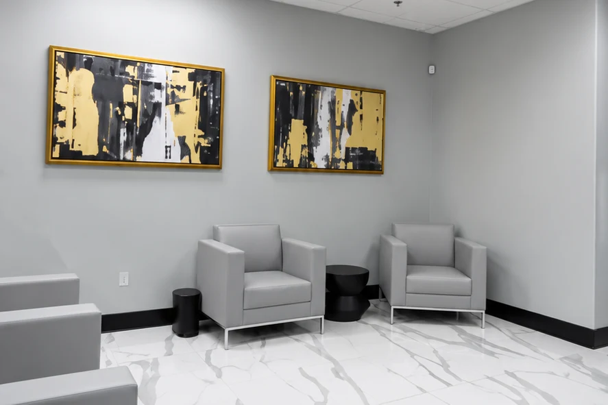 Open Ladah Law reception area with marble-look floor tile, gray seating, and acoustic ceiling panels.