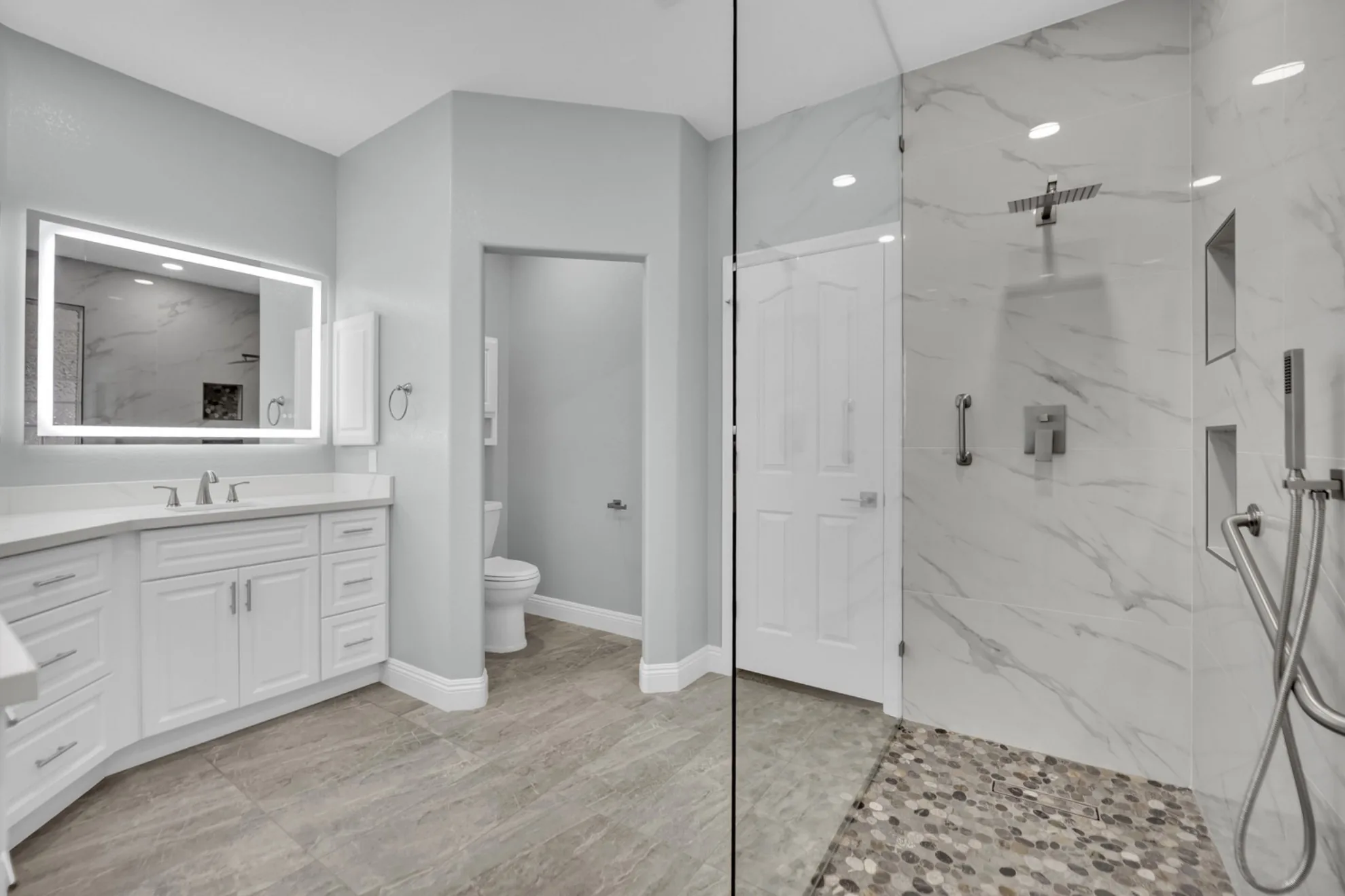 White shaker double vanity with lighted mirrors, quartz countertop, and added bathroom storage