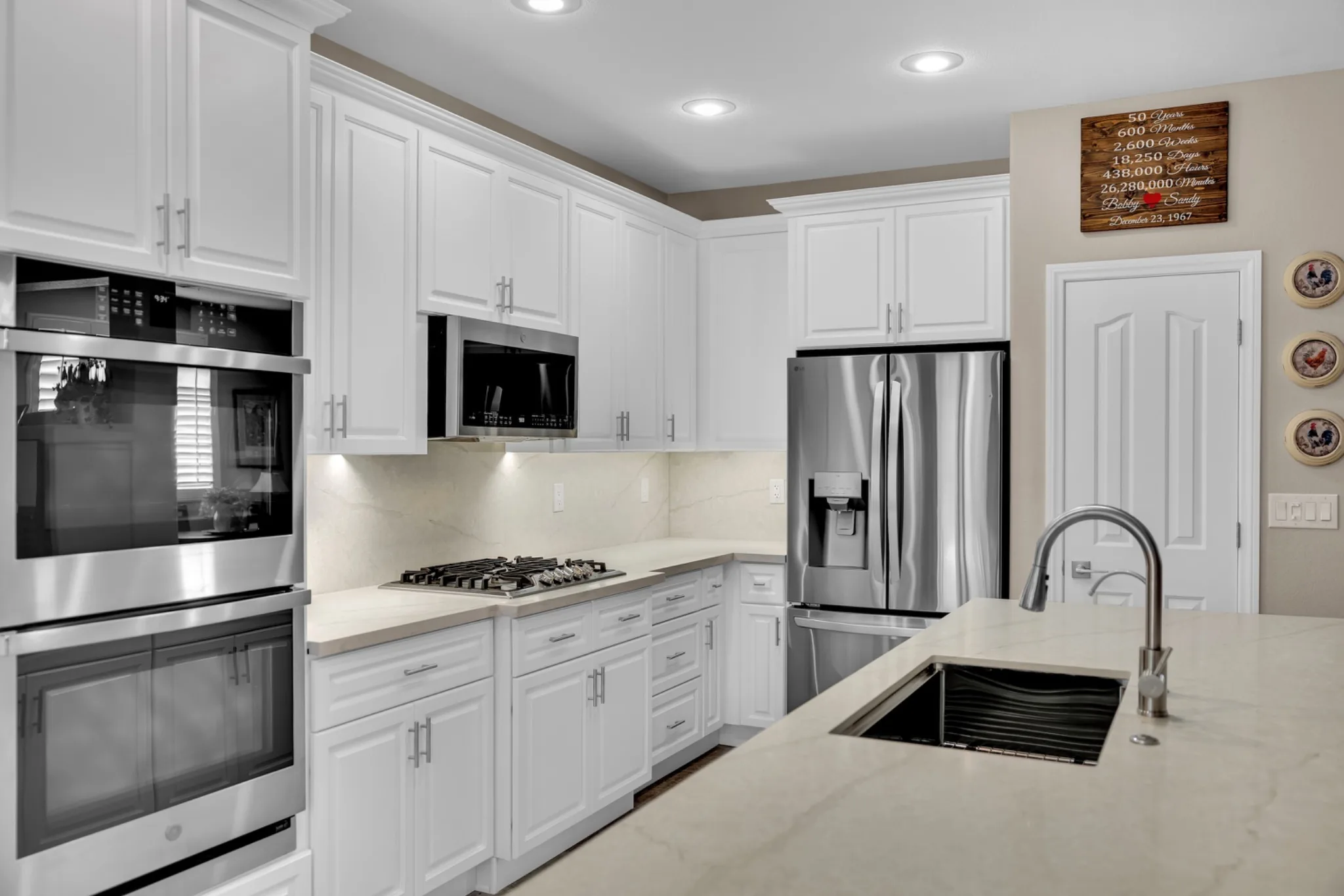 Expanded single-level kitchen island with sink and leathered quartz countertop in a prefab kitchen remodel