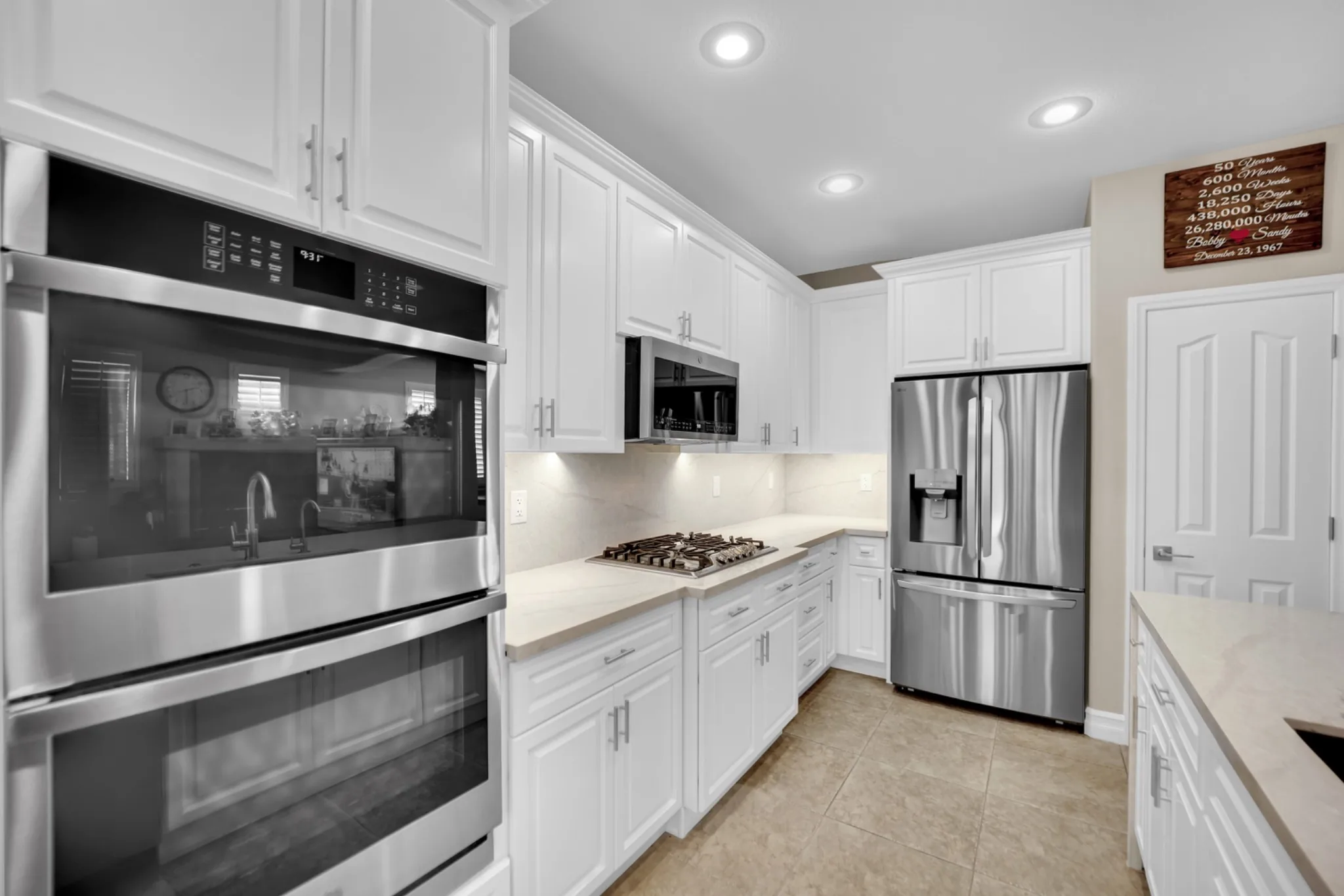Finished prefab kitchen remodel with new white cabinets, stainless appliances, recessed lighting, and existing floor tile