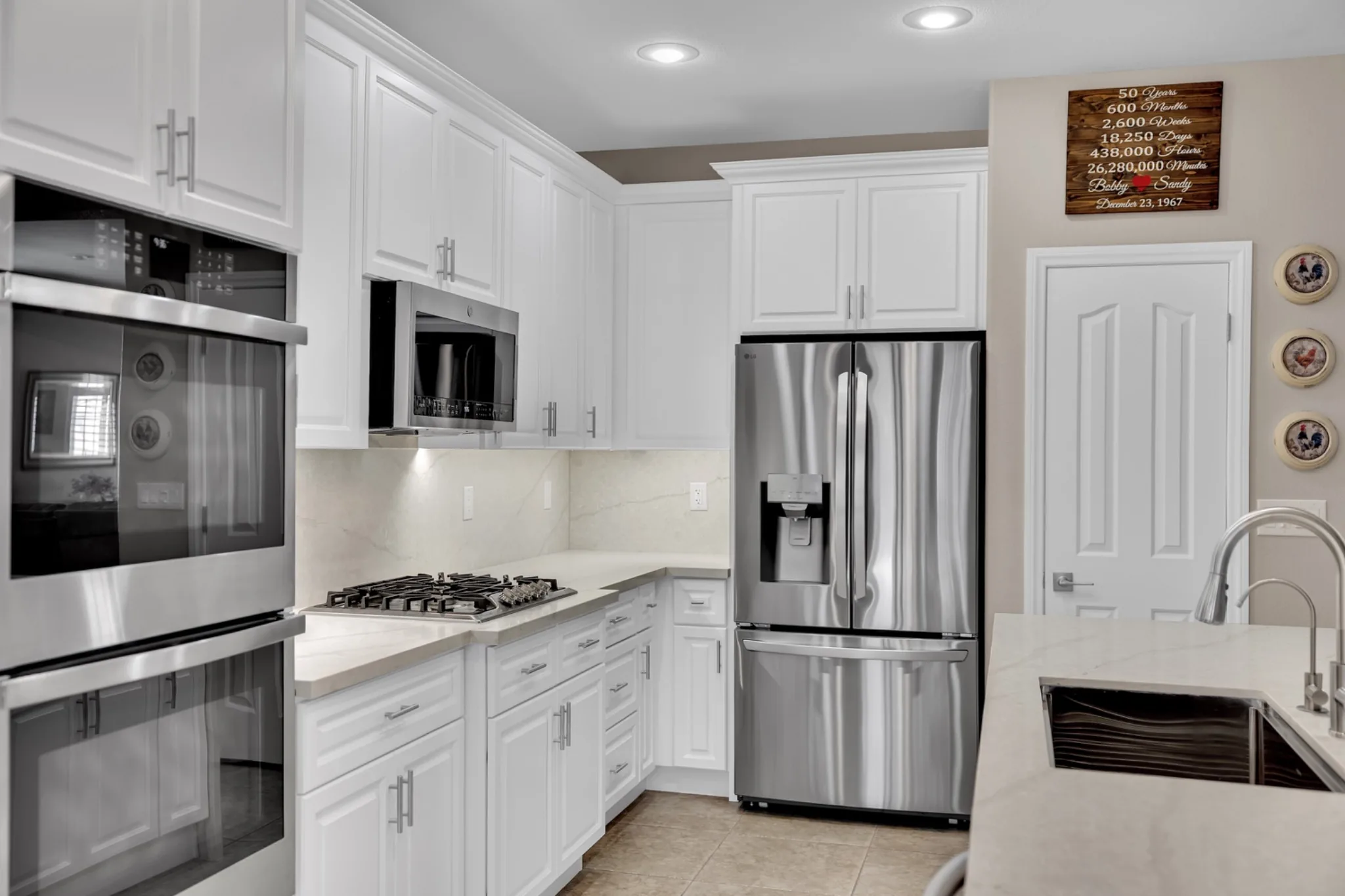 Under-cabinet lighting above leathered quartz backsplash and cooktop in the prefab kitchen remodel