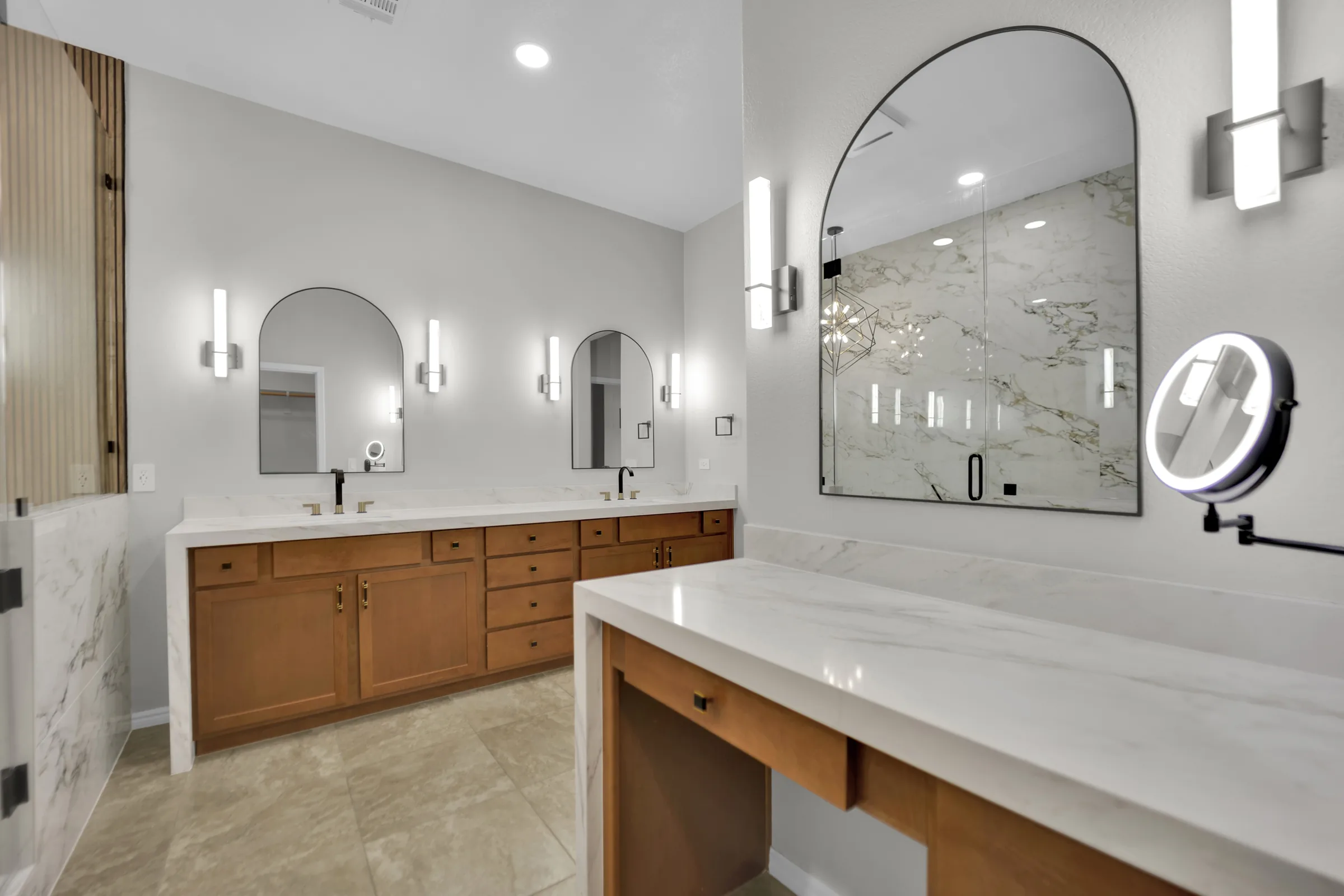 Makeup counter and double vanity with matching white countertops and wood cabinetry.