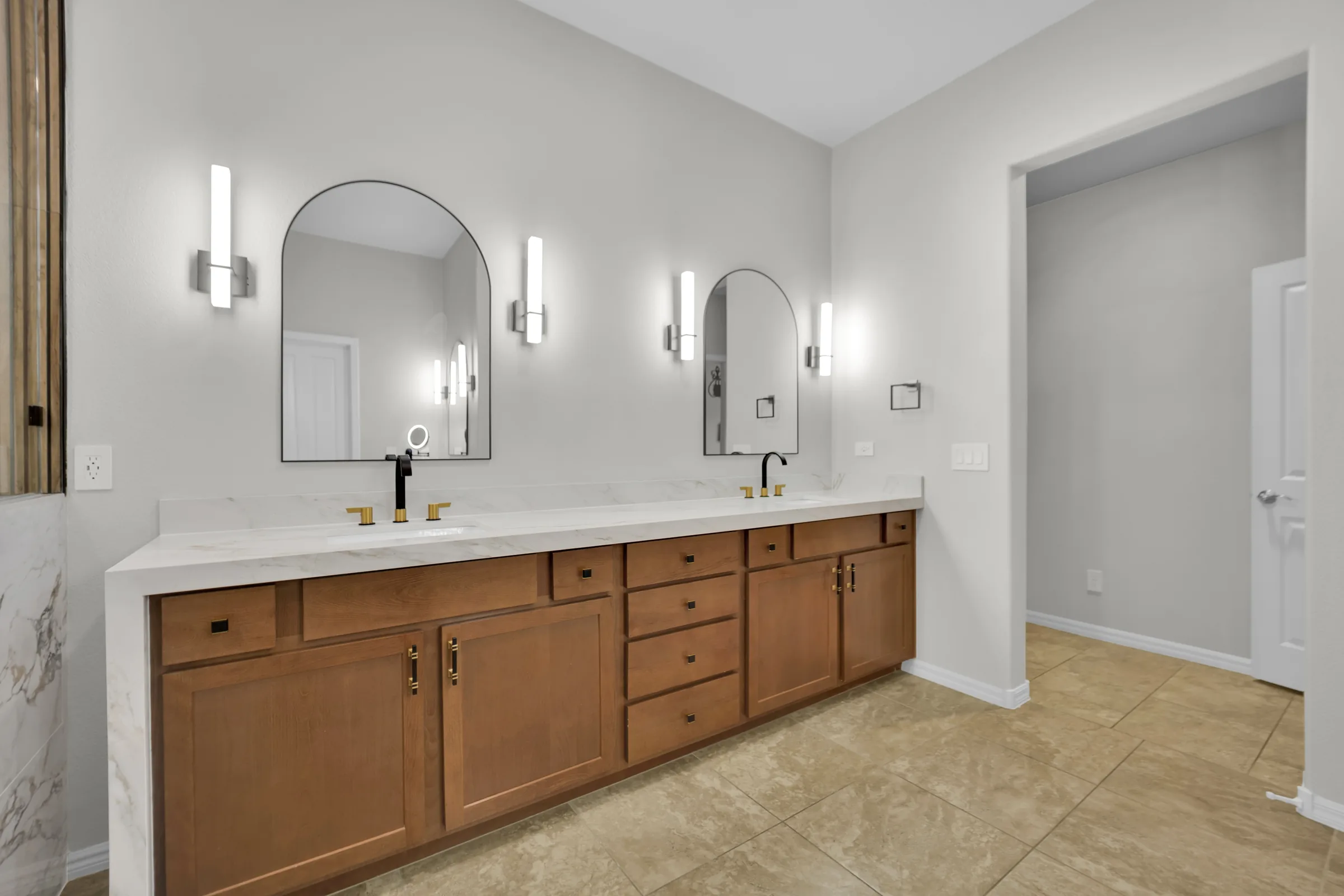 Retained wood double vanity with new white countertops, waterfall end, and arched mirrors.