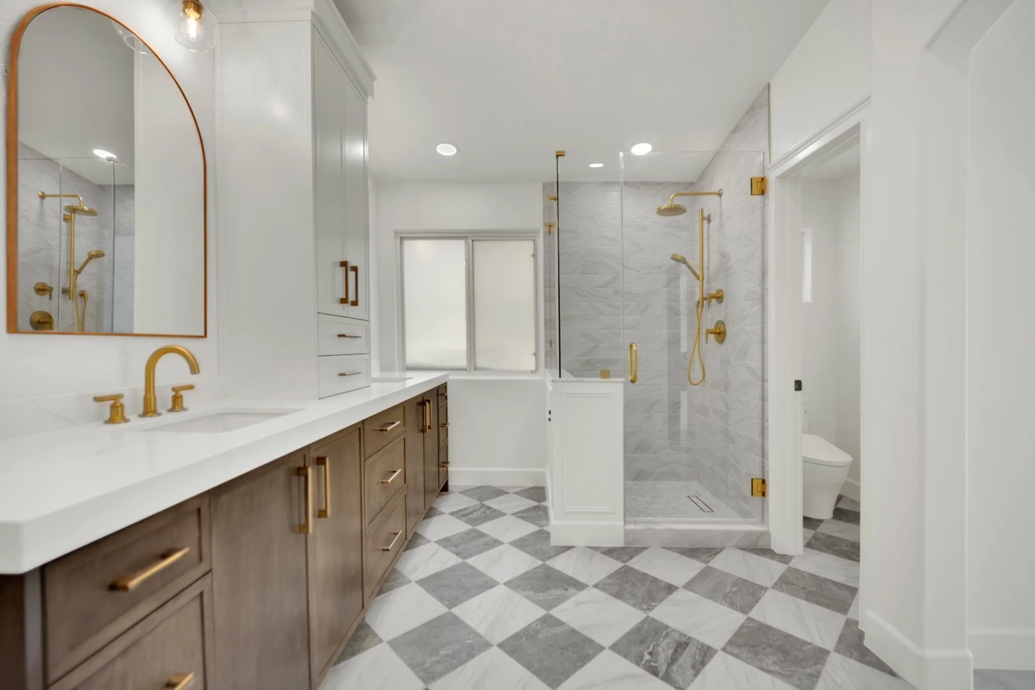 Enlarged marble shower with custom glass, gold fixtures, and raised shower head