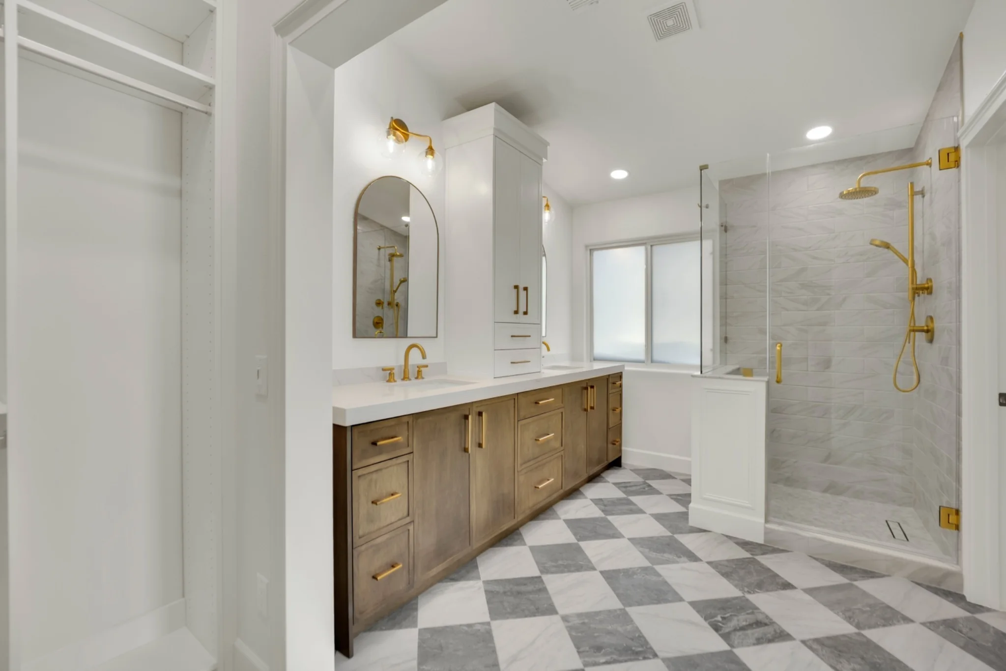 Primary bathroom remodel with marble shower, white oak vanity, quartz countertop, custom closet opening, checkered marble floor, and gold fixtures