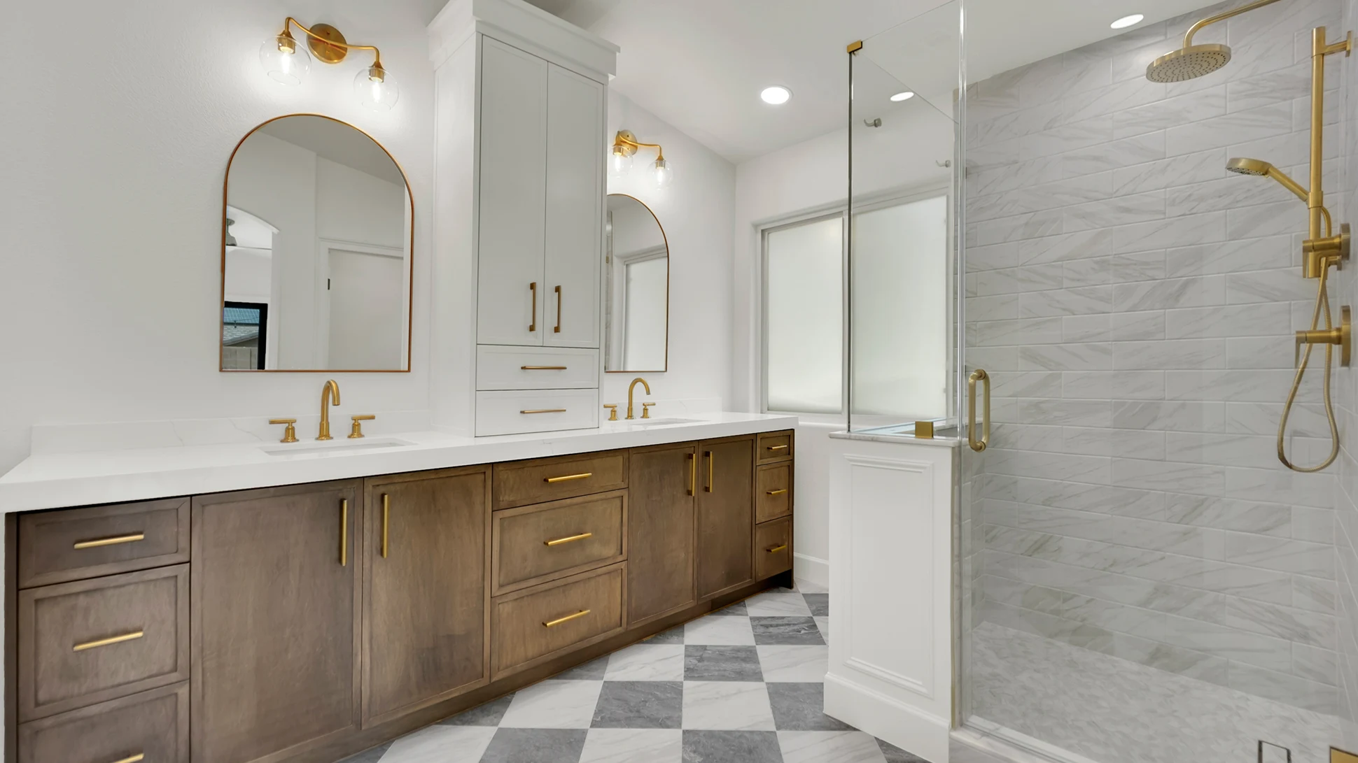 Finished primary bathroom after the remodel with enlarged marble shower, custom glass, white oak vanity, quartz countertop, gold fixtures, and checkered marble floor