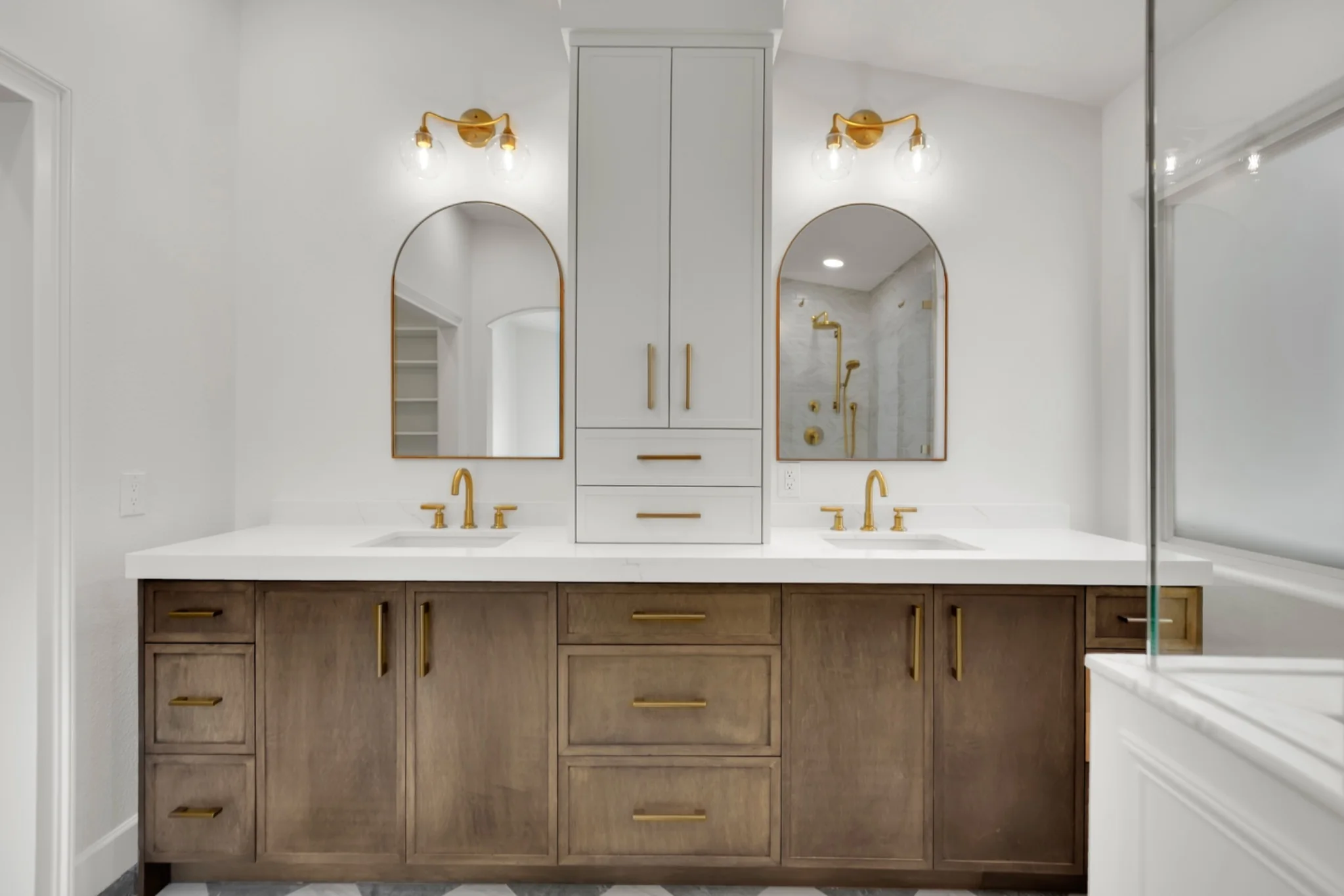 White shaker center tower above stained white oak vanity with quartz countertop and arched mirrors