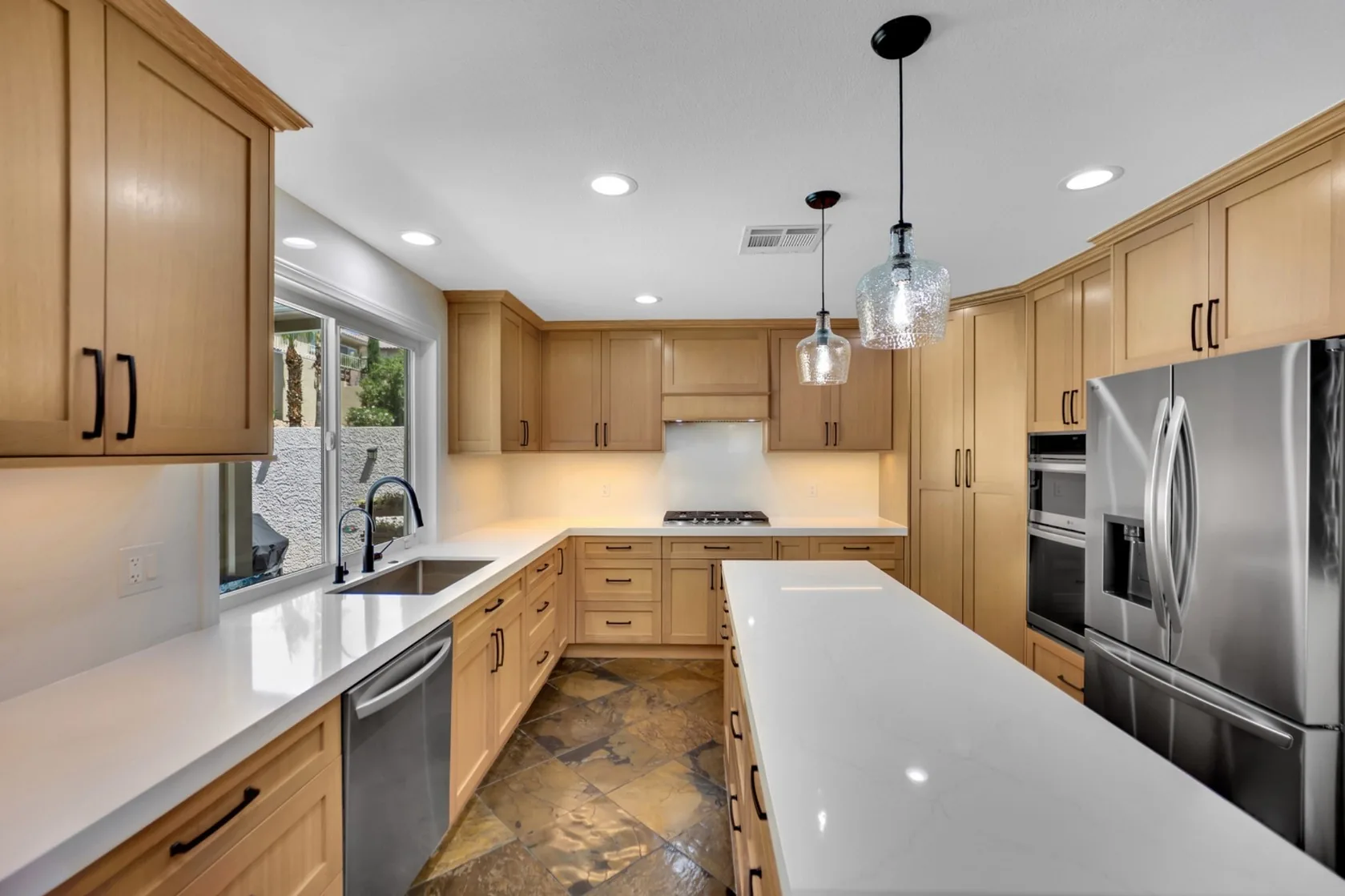 Custom rift white oak kitchen remodel with sink under window, island, pendants, and under-cabinet lighting