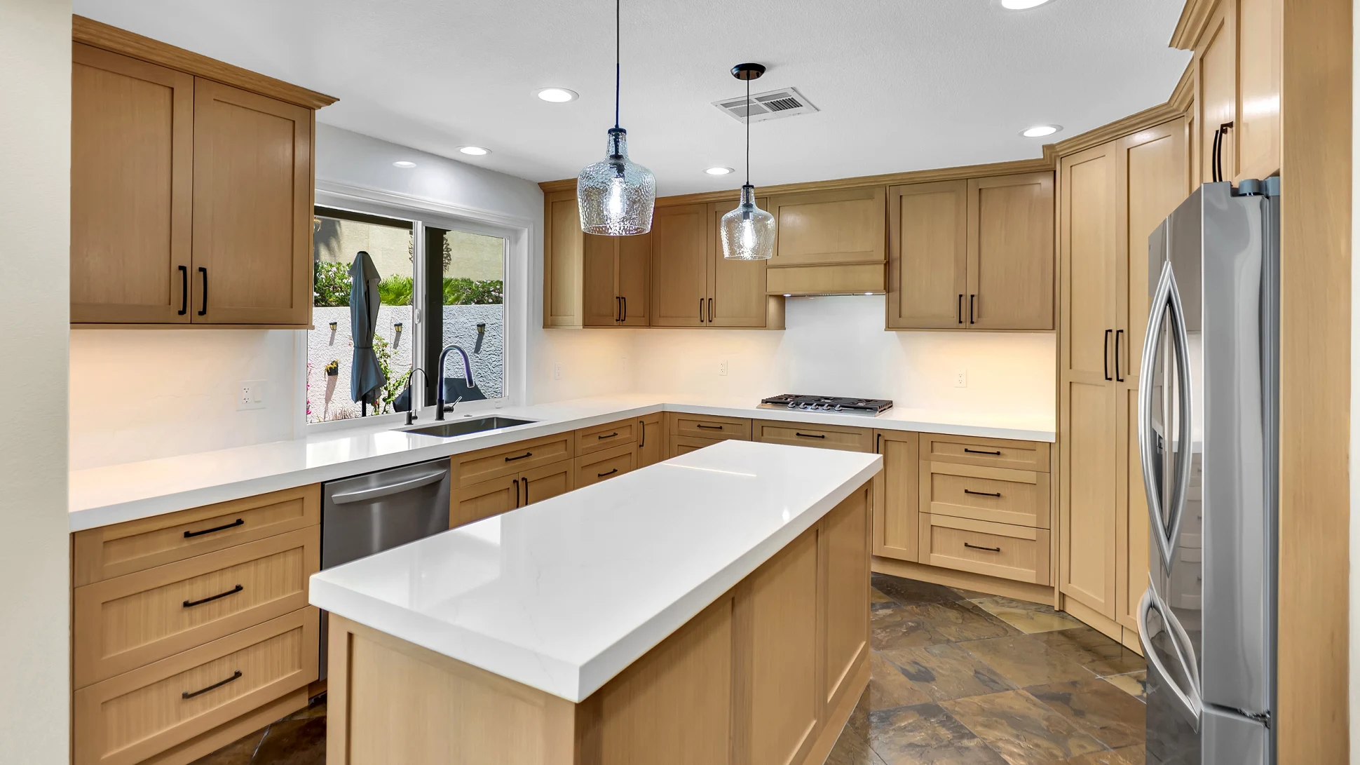 Finished rift white oak custom kitchen remodel with Cambria white quartz, improved pantry storage, pendant lights, and retained stone tile flooring