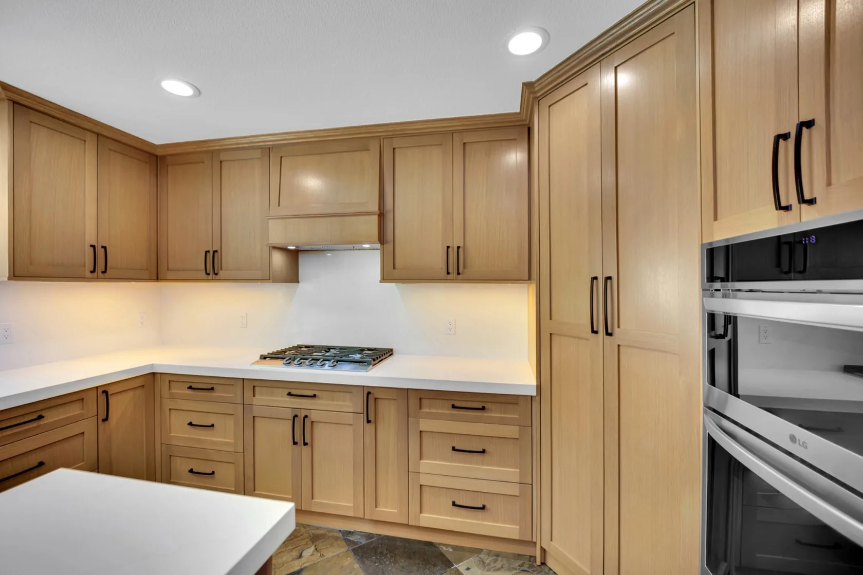 Rift white oak cooktop wall with white quartz backsplash and under-cabinet lighting