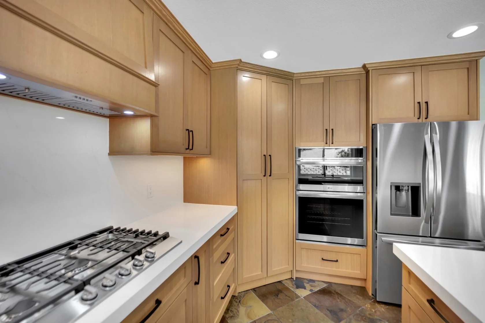 Tall rift white oak pantry cabinets with built-in oven, refrigerator wall, and black hardware