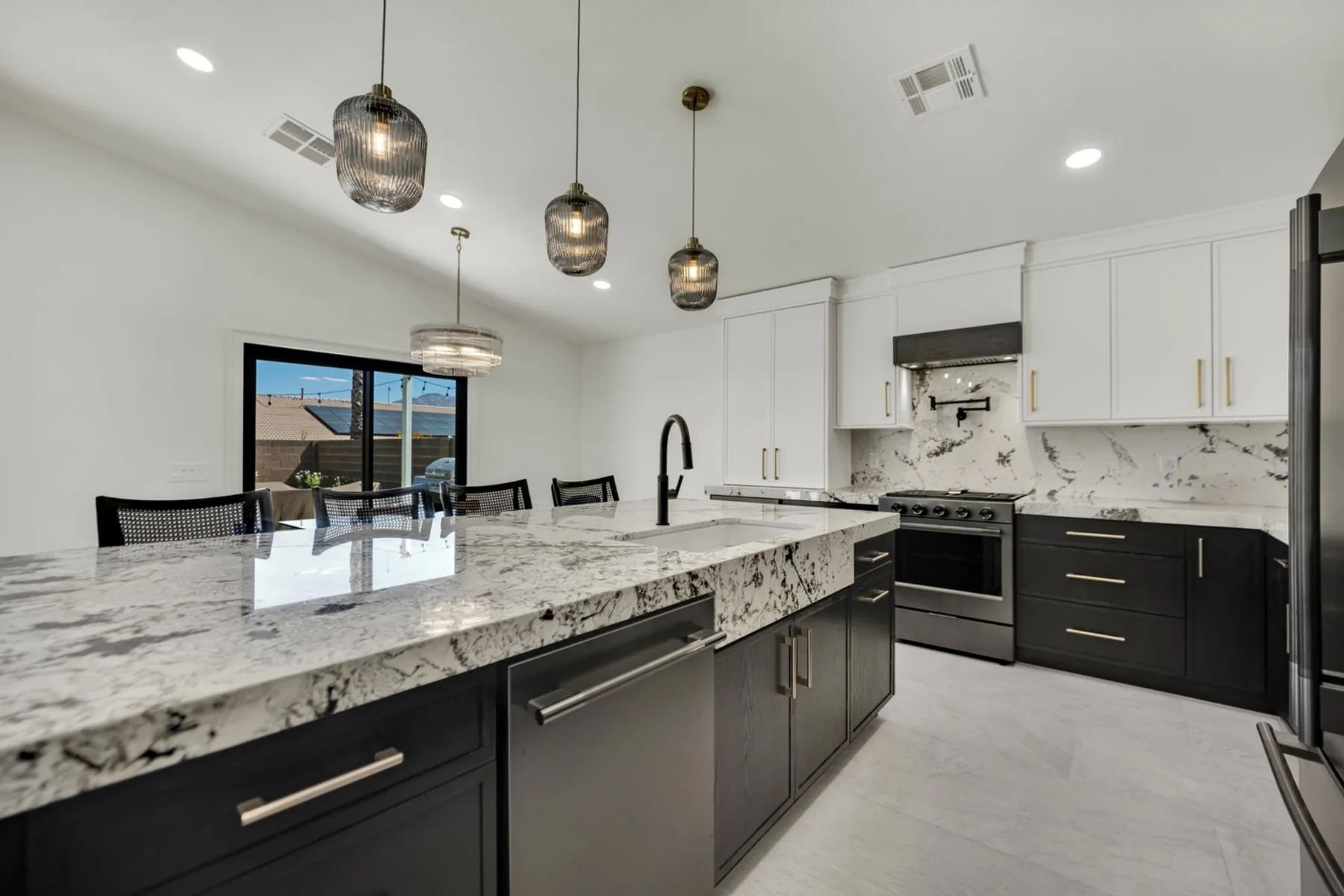 Finished Summerlin kitchen remodel with granite island, pendant lights, custom cabinetry, and full-height backsplash