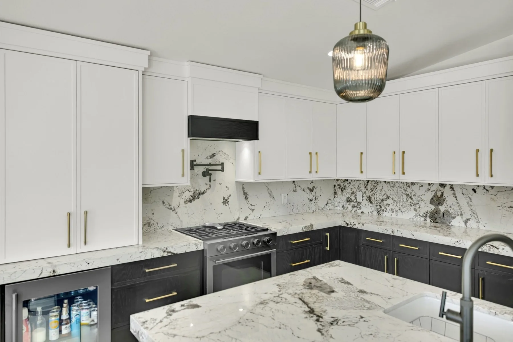 Full-height granite slab backsplash with cream shaker cabinets and dark painted lower cabinets in Summerlin kitchen remodel