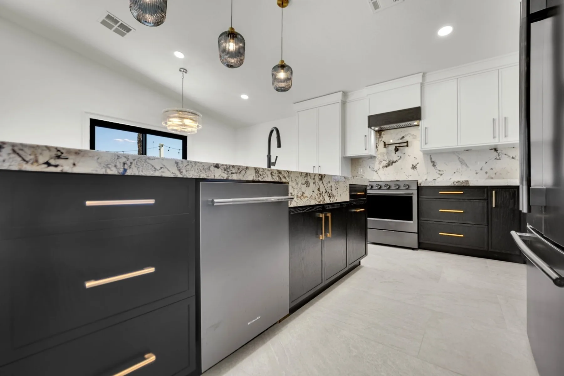 Custom kitchen island with painted white oak cabinetry, 2-inch mitered granite countertop, and matte black faucet in Summerlin