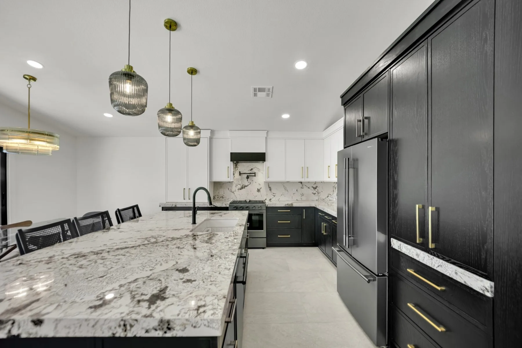 Summerlin custom kitchen remodel with integrated refrigerator wall, granite island, pendant lighting, and matte black faucet
