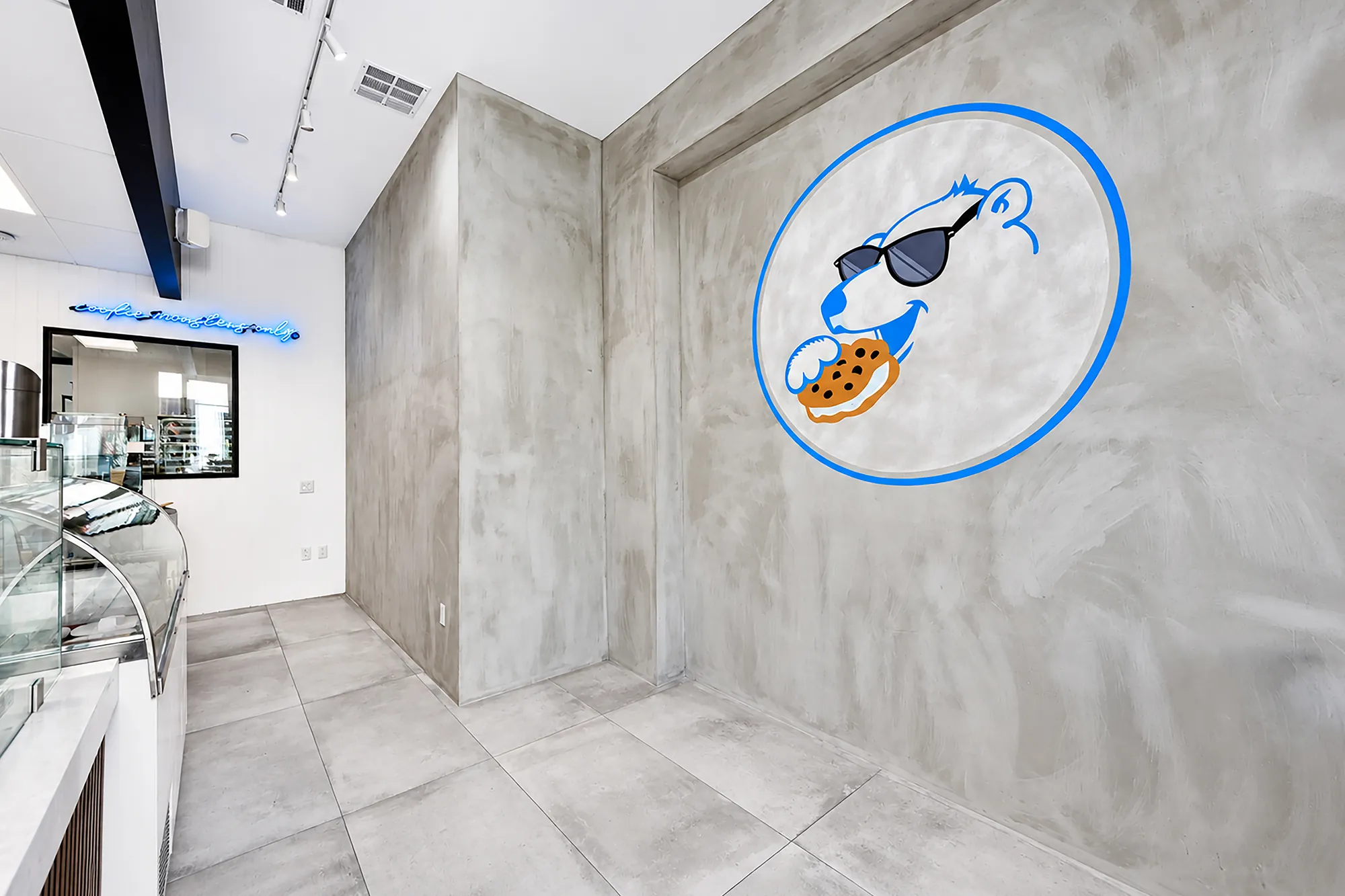 Baked Bear logo on the gray microcement feature wall beside the customer walkway