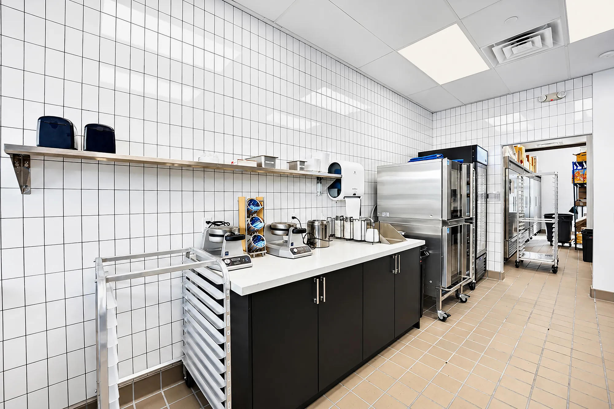 White preparation counter with warming equipment, black base cabinets and stainless refrigeration at The Baked Bear