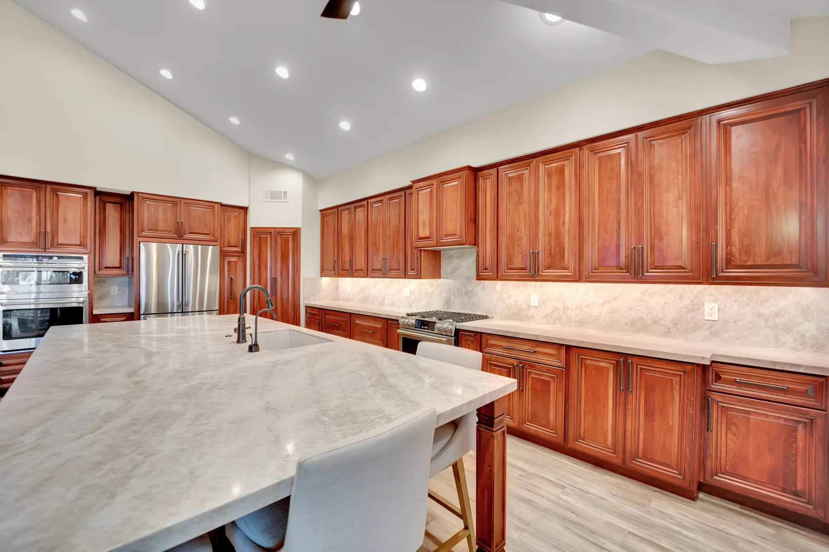 Bookmatched Taj Mahal kitchen island with sink, seating, and custom maple cabinetry