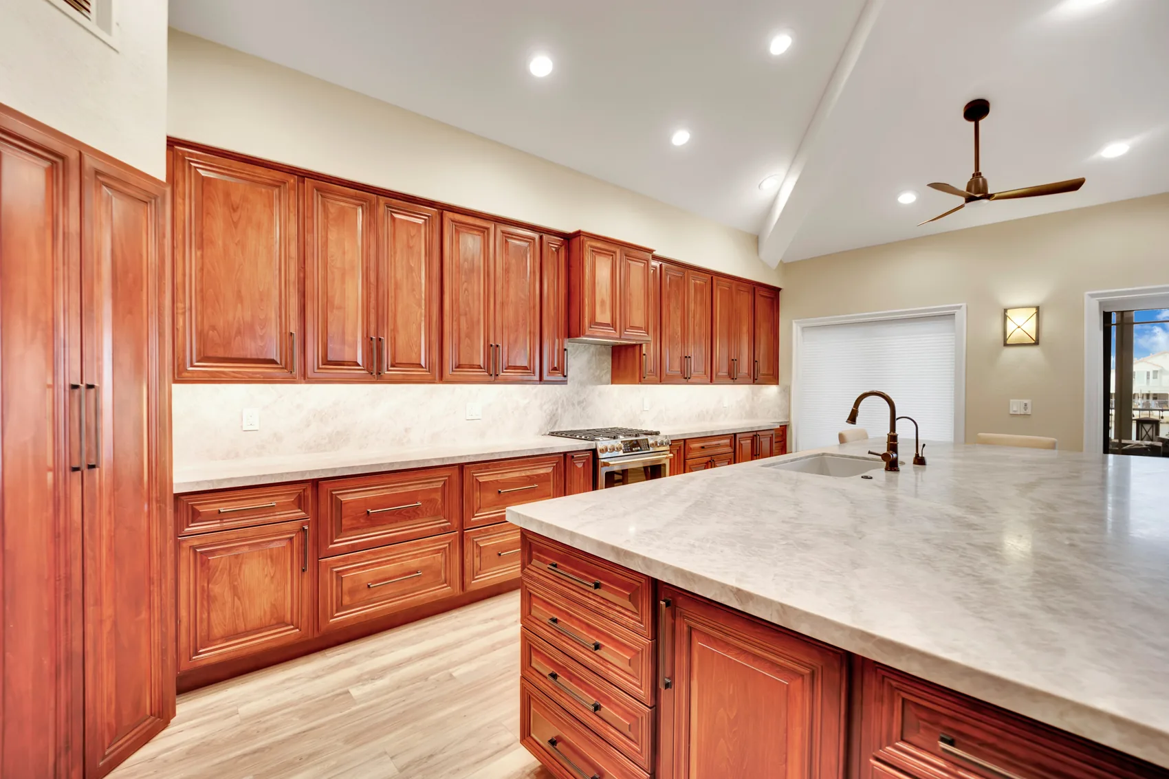 Custom stained maple kitchen cabinets with under-cabinet lighting and Taj Mahal slab backsplash