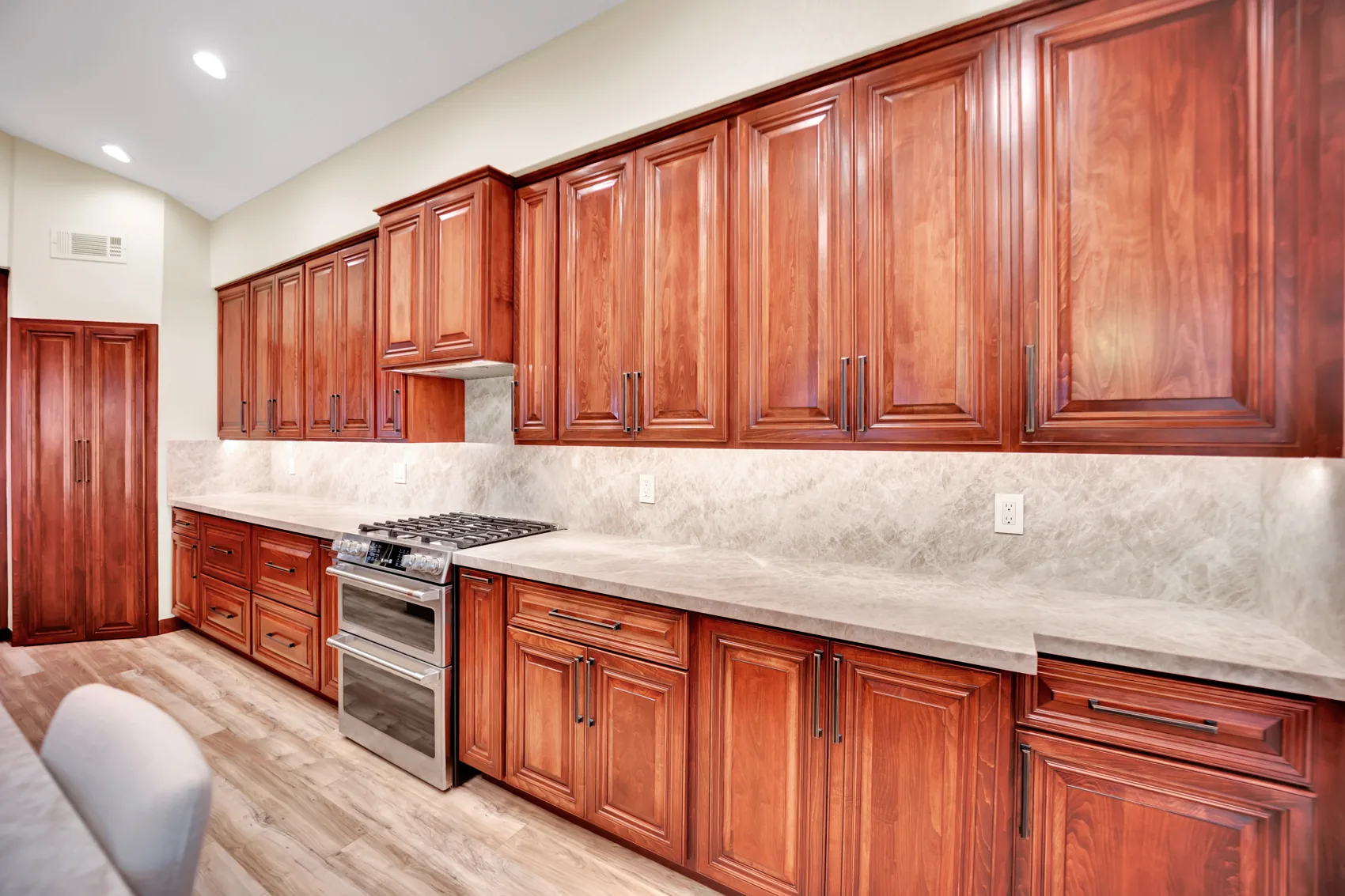 Raised-panel maple cabinets with leathered Taj Mahal countertop and full-height slab backsplash