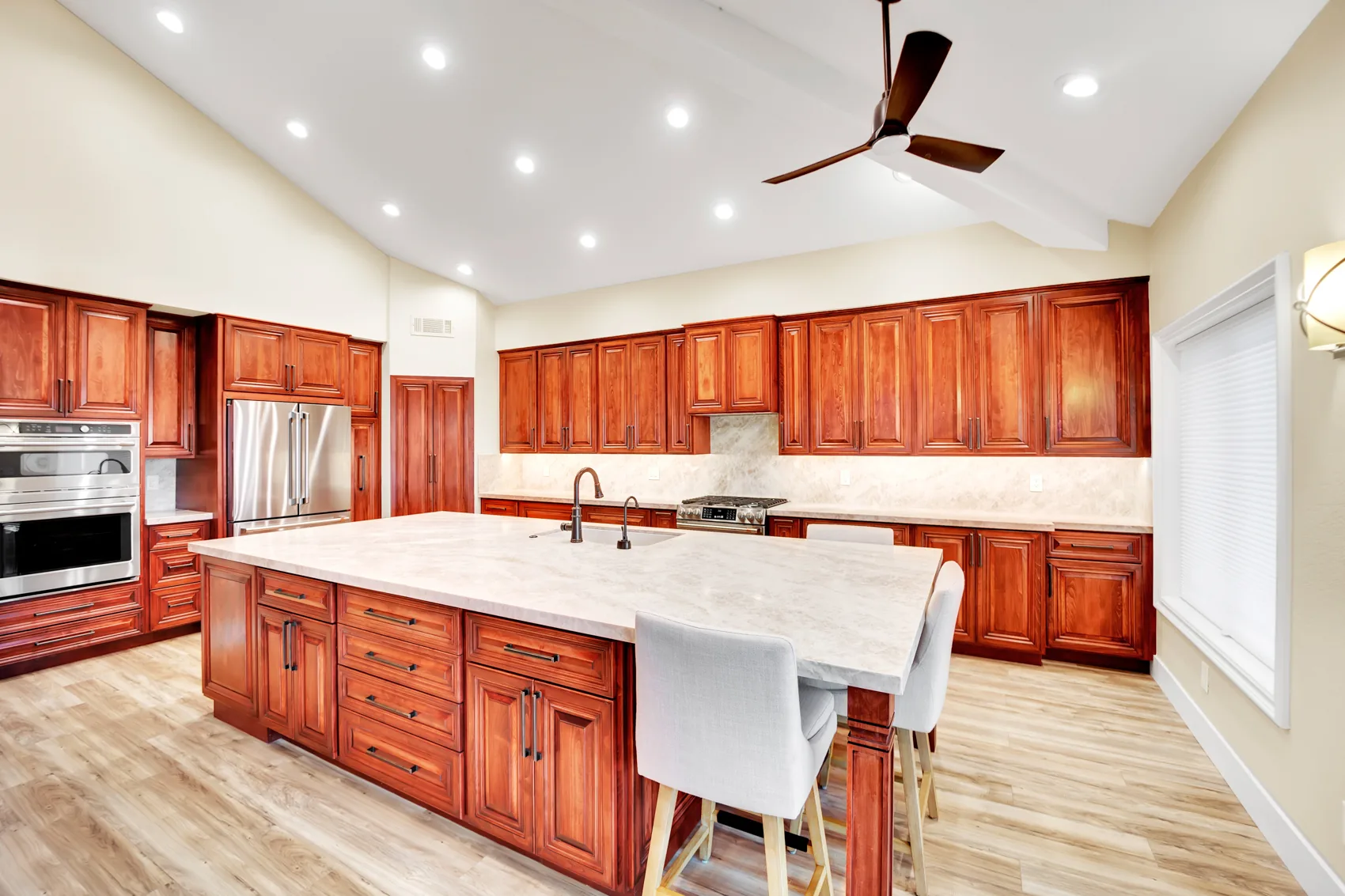 Custom maple kitchen remodel with stained maple cabinets, Taj Mahal countertops, and large island seating