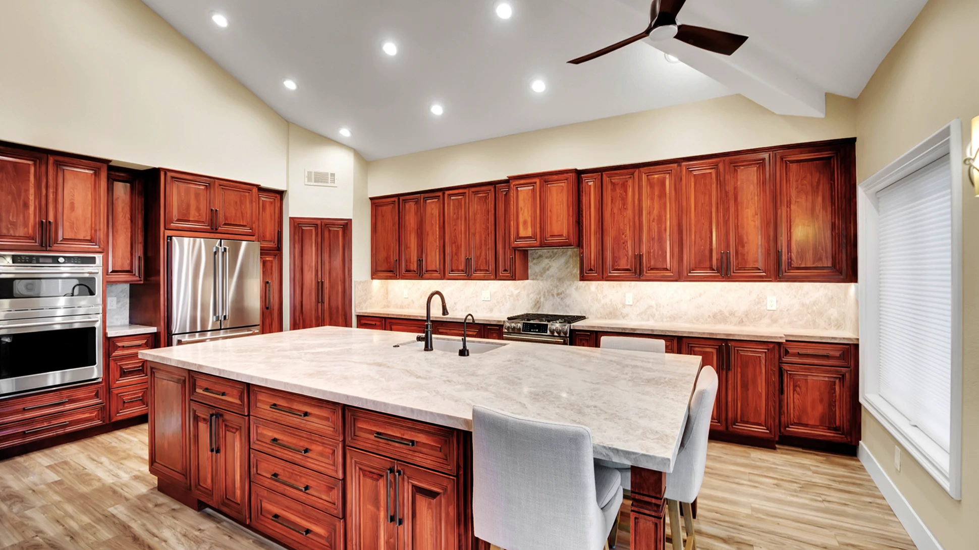 Finished custom maple kitchen remodel with Taj Mahal island, slab backsplash, GE Cafe appliances, and custom stained cabinets