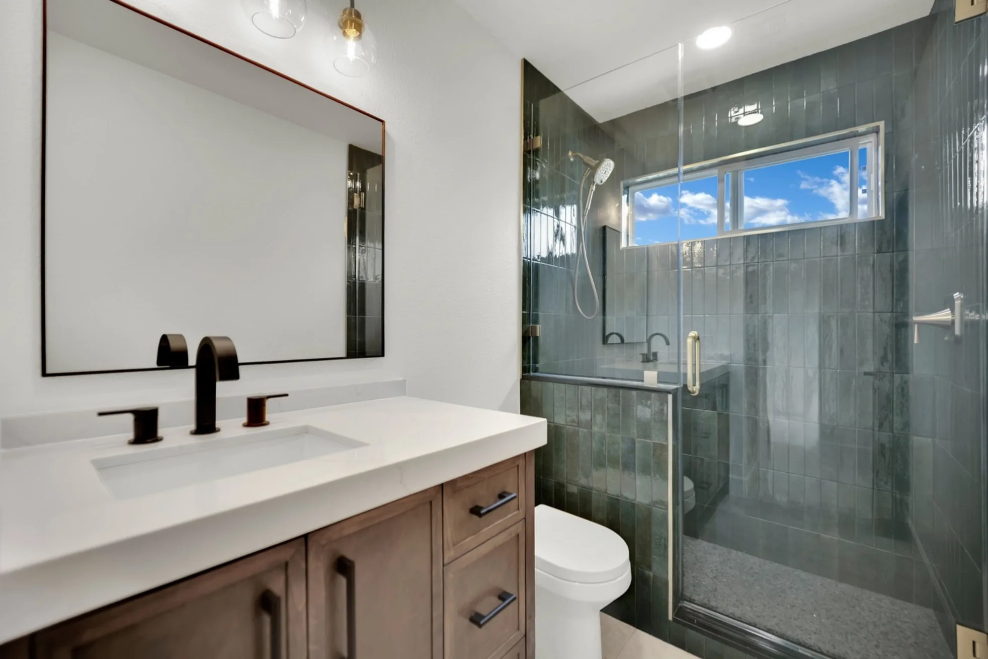 Walk-in shower with glossy Moroccan-style ceramic tile, pony wall, hidden niche, custom glass, and warm metal accents