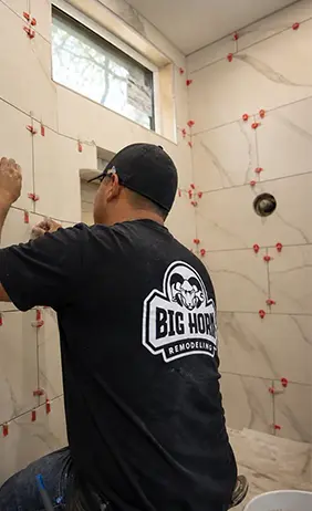 Tile installer aligning shower-wall tiles with spacers